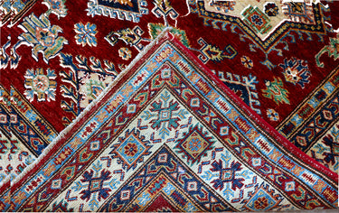 edge of a hand knotted medium red white kazak afghan rug